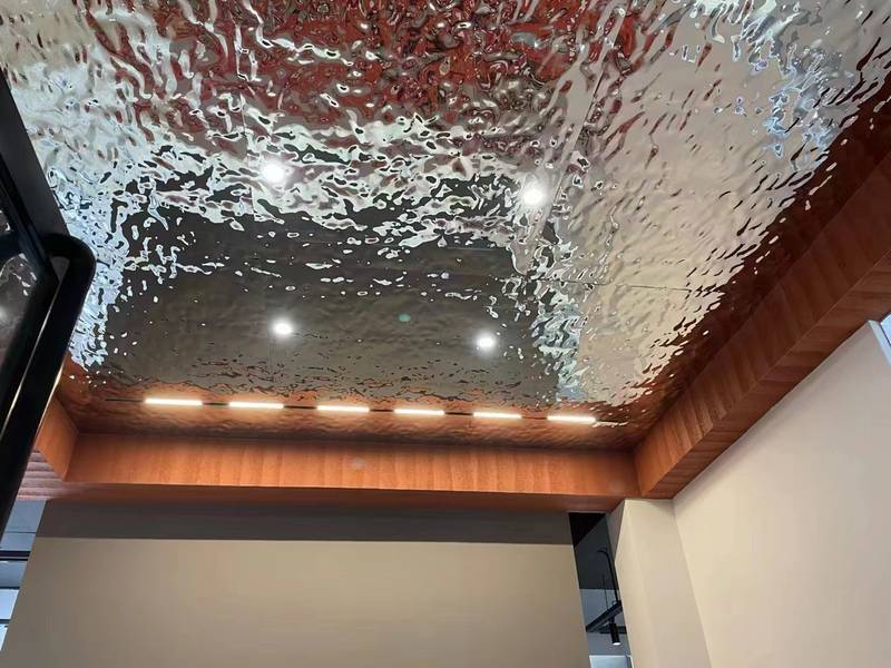 Water ripple stainless steel ceiling in a cafe and bar interior with hanging pendant lights